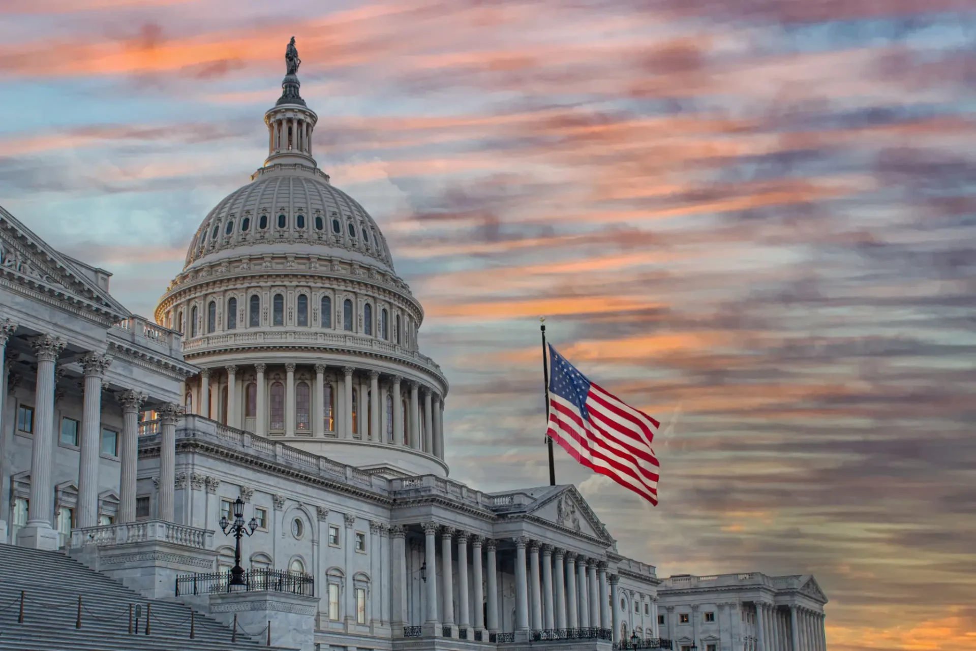 The U.S. Capitol with the American flag at sunset.